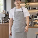 Tạp dề đồng phục màu ghi sáng, túi ngực nhỏ, form yếm cúc điều chỉnh, chất vải chống thấm